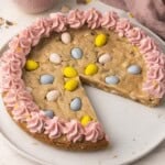 mini egg cookie cake on a white plate with a piece missing.