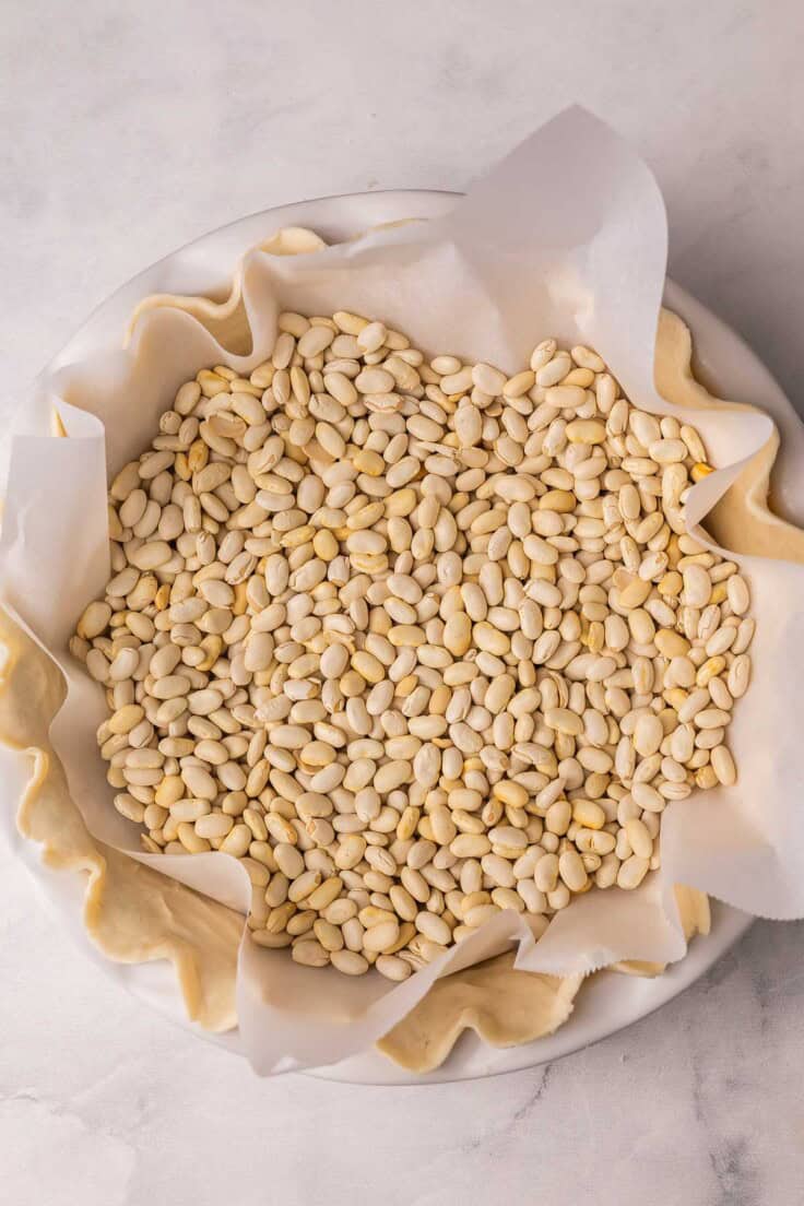 beans in a pie crust with parchment paper.