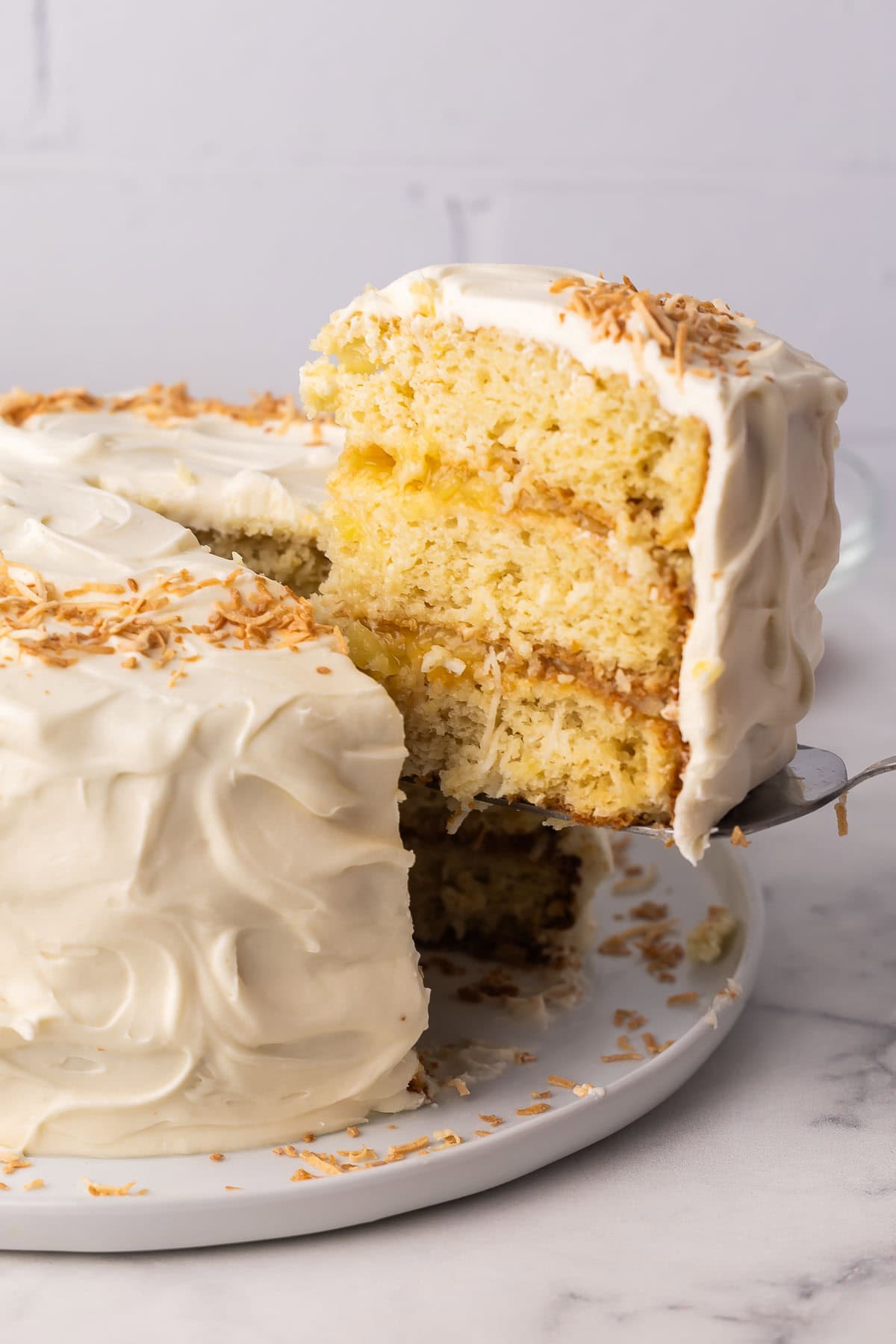 slice of pineapple coconut cake being lifted off of plate.