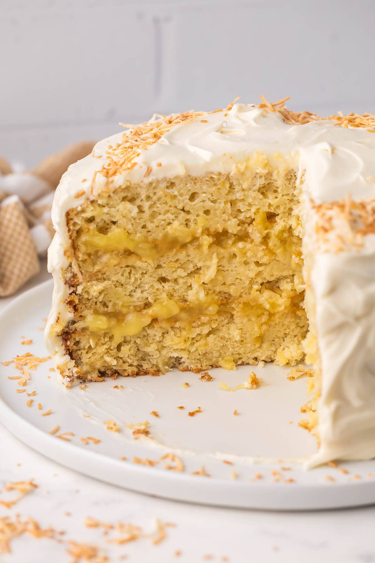 pineapple coconut cake on a white plate with a few pieces missing.