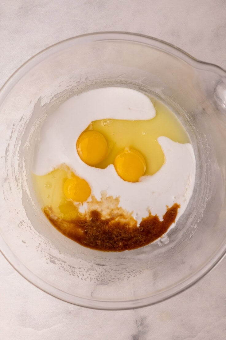 eggs and other wet ingredients added to glass mixing bowl.