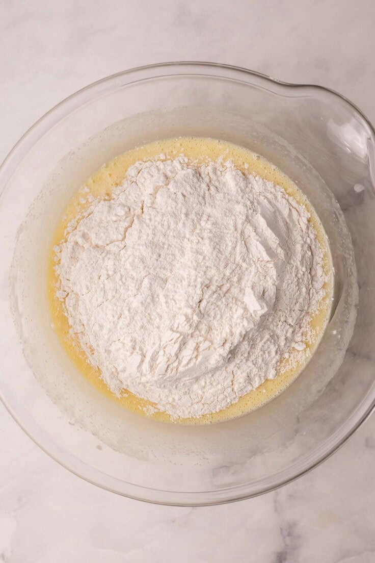 flour added to other ingredients in glass mixing bowl.