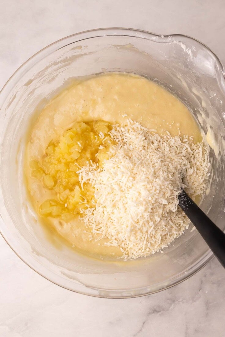 shredded coconut added to other ingredients in glass mixing bowl.