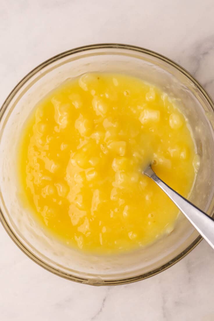 glass bowl full of pineapple sauce and spoon.