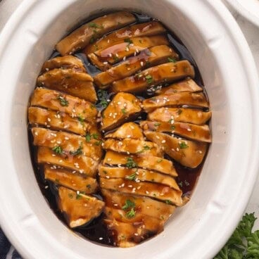 sweet and spicy coconut chicken in a white slow cooker.