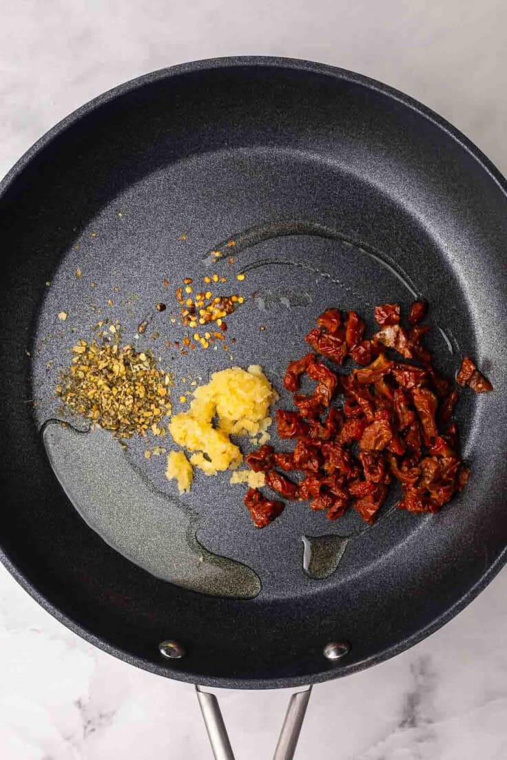 black pan with unmixed spices and sun dried tomatoes.