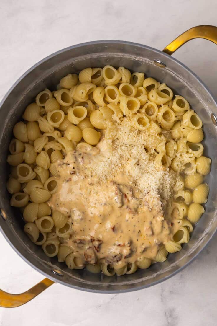 sauce and shredded cheese added to pot of cooked pasta.