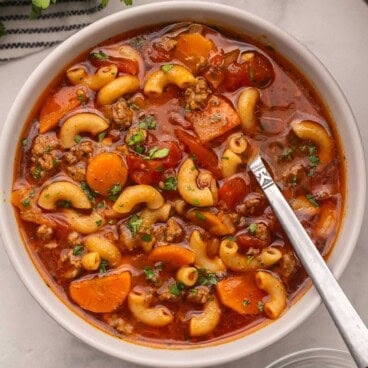 beef and tomato macaroni soup in a bowl topped with chopped parsley.