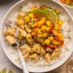 mango chicken rice bowls with lime wedges and fork stuck in rice.