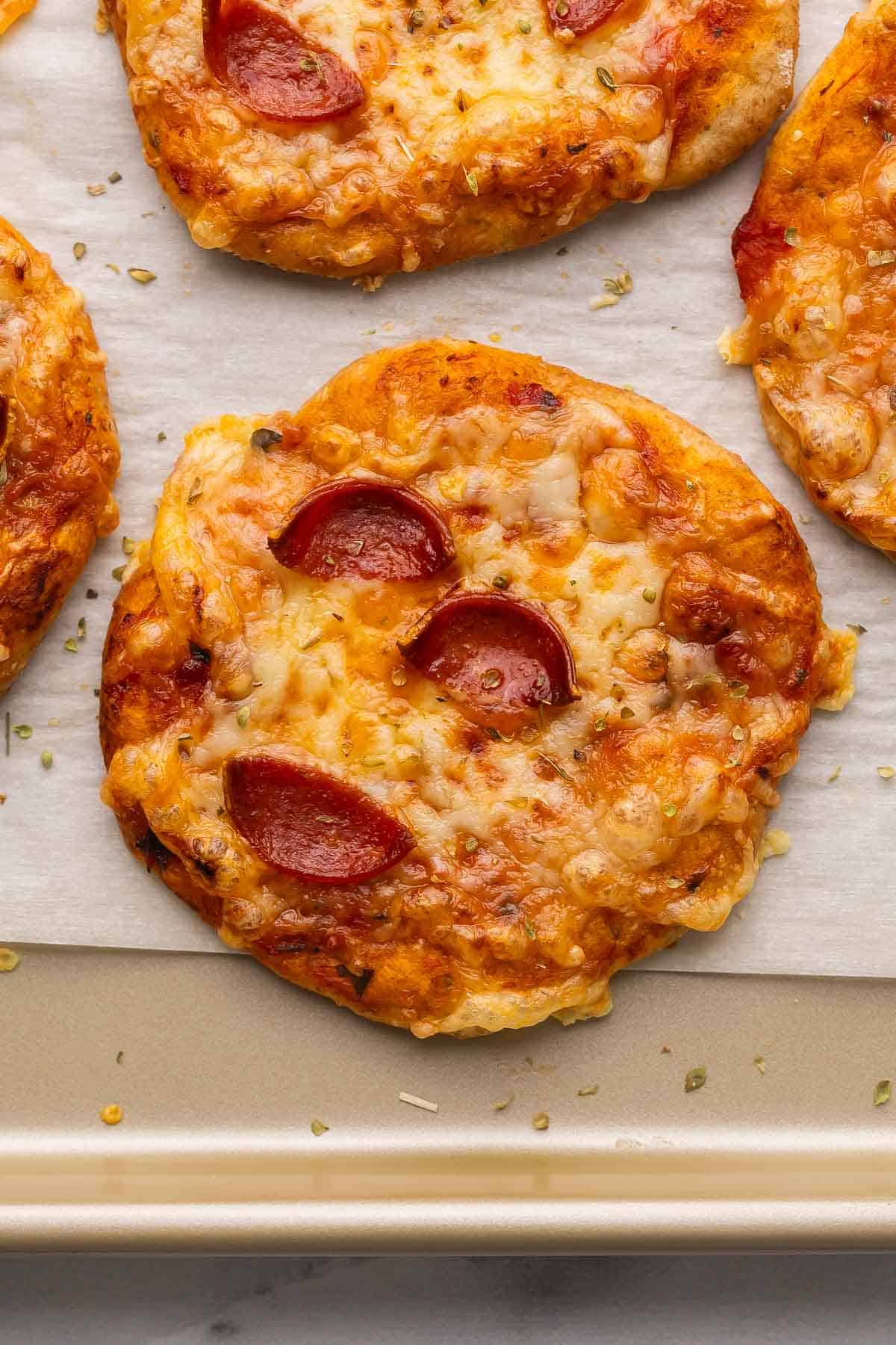 Pizza Buns are easy, cheesy handheld bites made with pizza dough, pizza sauce, shredded cheese, and pepperoni. They’re kid-friendly, portable, customizable, and great for lunches, snacks, or quick dinners! #pizza #dinner #recipe | easy recipes | pizza recipes | lunch ideas | lunches for kids | family recipes | freezer friendly | pepperoni | cheese a pepperoni pizza bun on parchment in pan.
