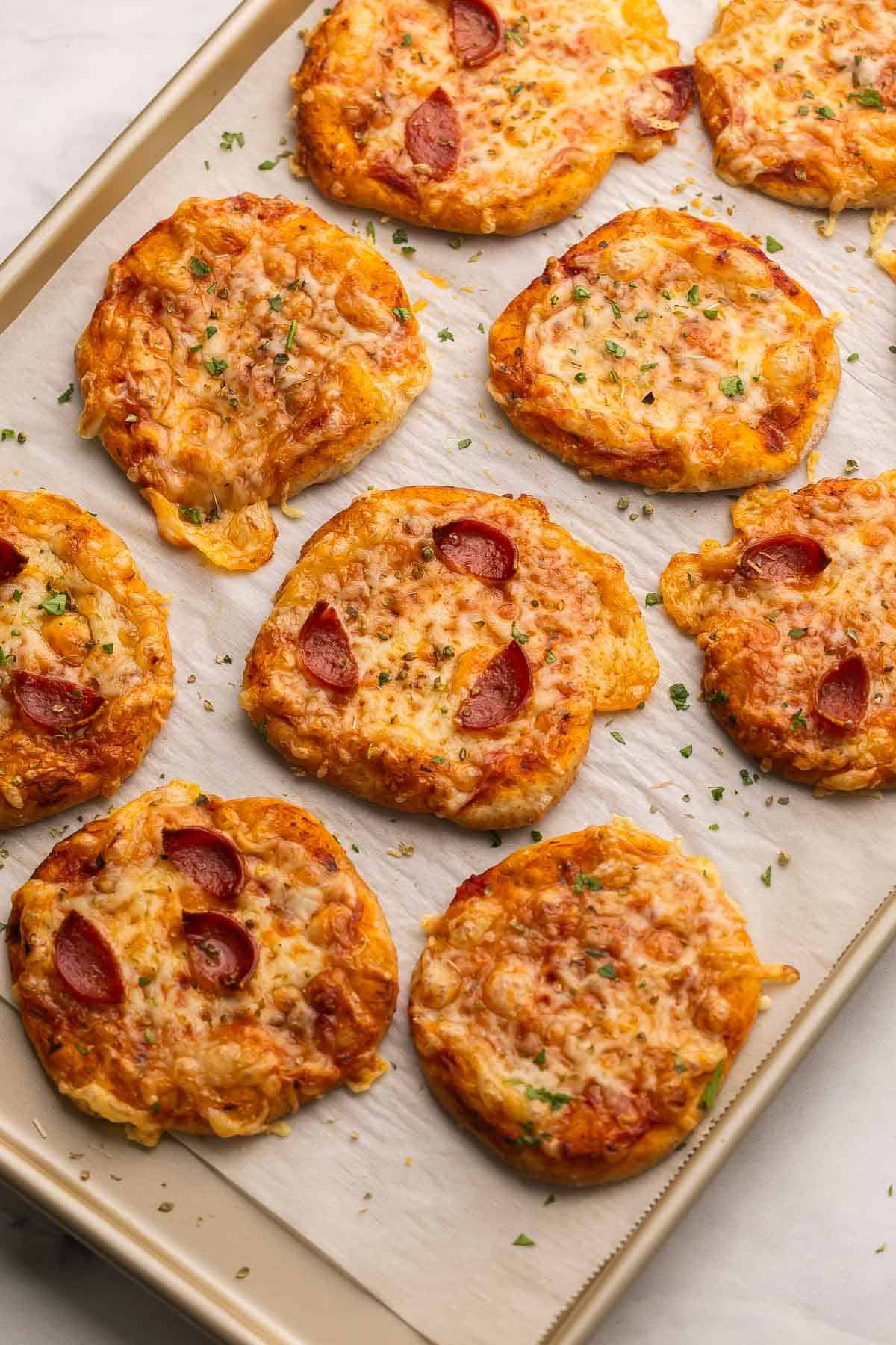 Pizza Buns are easy, cheesy handheld bites made with pizza dough, pizza sauce, shredded cheese, and pepperoni. They’re kid-friendly, portable, customizable, and great for lunches, snacks, or quick dinners! #pizza #dinner #recipe | easy recipes | pizza recipes | lunch ideas | lunches for kids | family recipes | freezer friendly | pepperoni | cheese a pan full of baked pizza buns.
