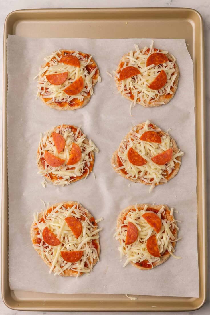 six homemade pizza buns on a pan ready to be baked.