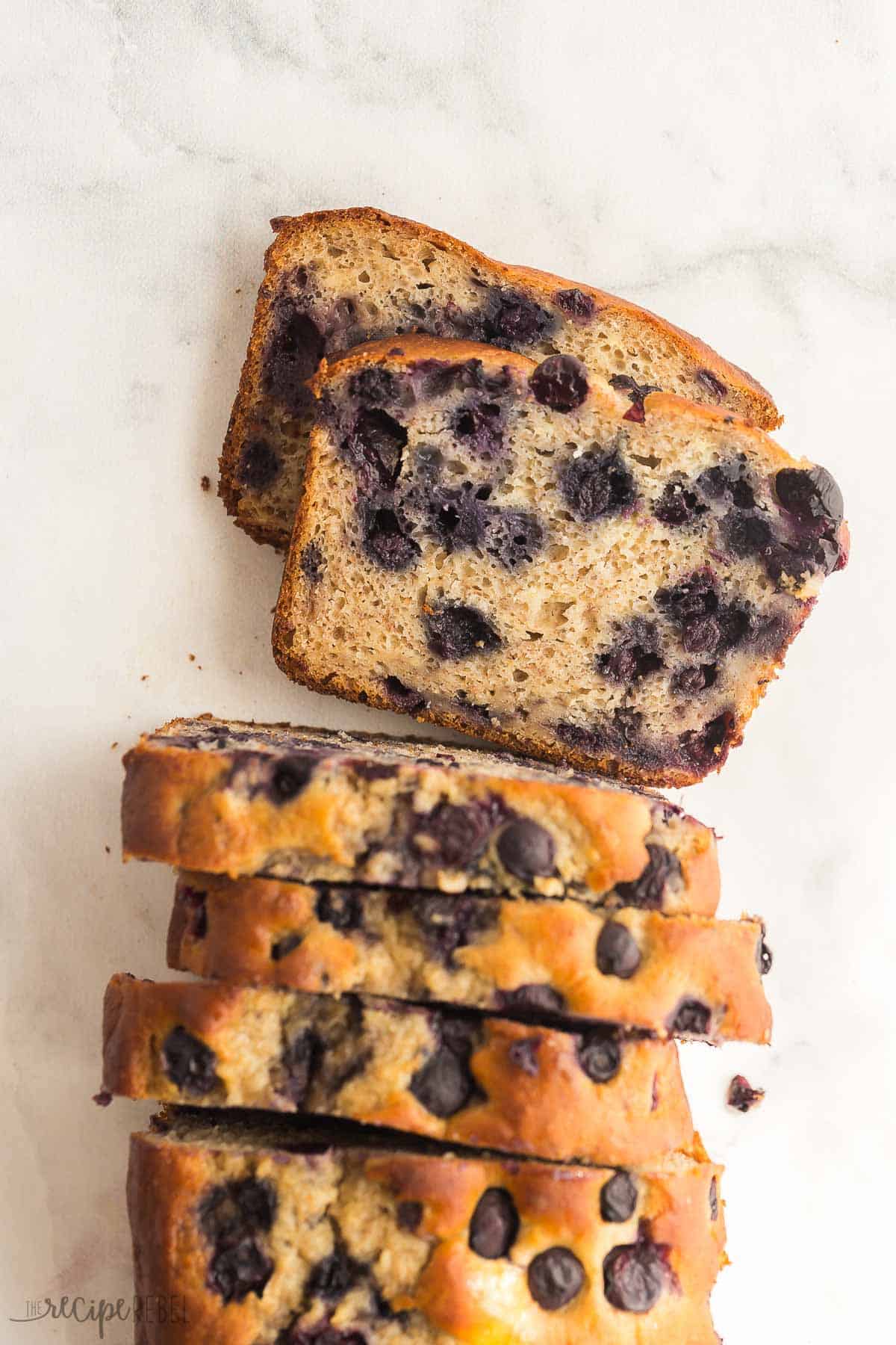 This Blueberry Banana Bread is ultra moist and tender, loaded with bananas and blueberries! Use fresh or frozen blueberries and fresh or frozen bananas -- it's perfect for breakfast on the go. #banana #blueberry #baking #recipe | banana bread recipes | blueberry recipes | banana recipes | baking recipes | breakfast ideas | on the go breakfast | kids lunch overhead image of blueberry banana bread with slices cut.