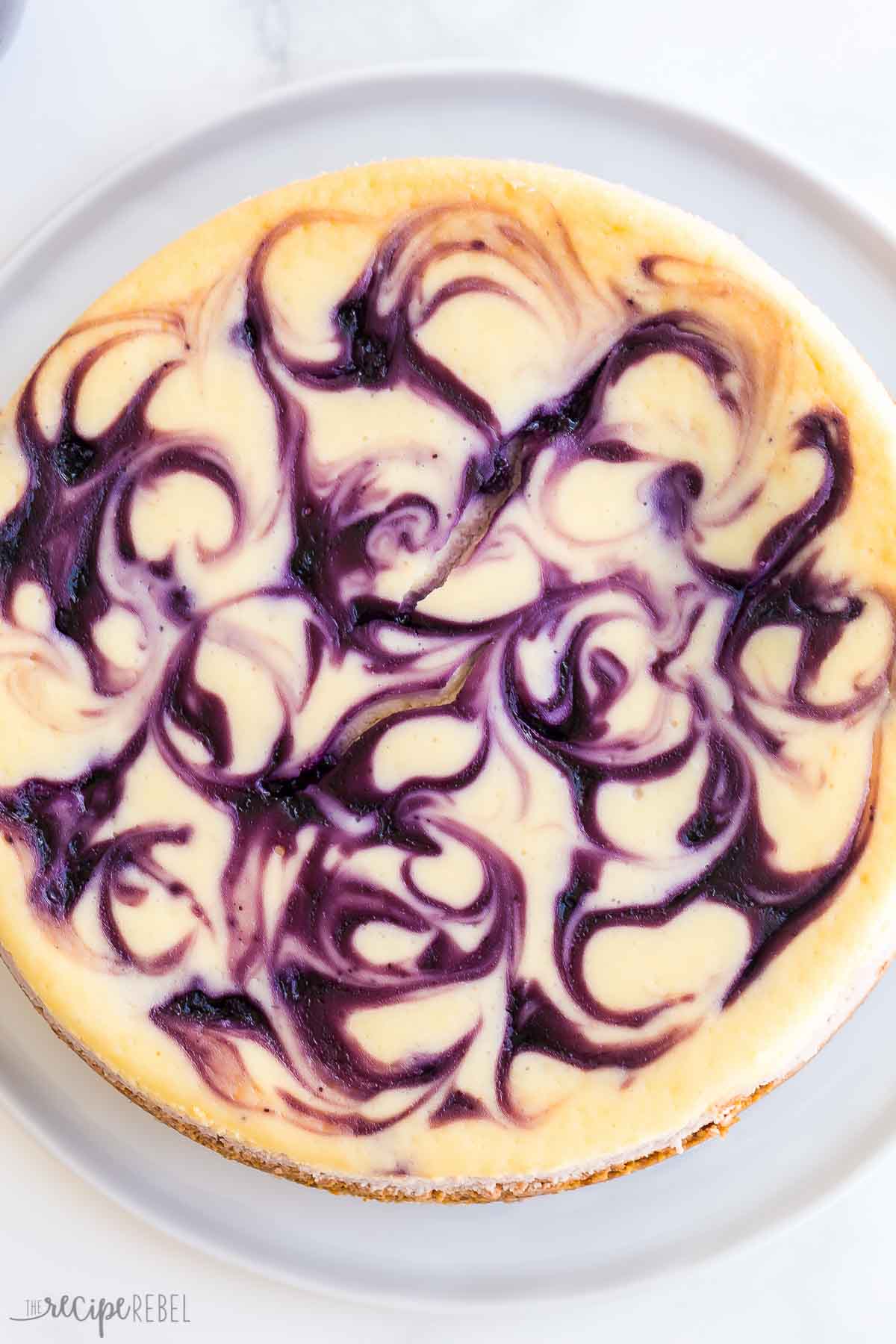 This Blueberry Cheesecake is ultra creamy and swirled with fresh blueberry sauce. It's made with no water bath and no fuss and is the perfect summer dessert! #blueberry #cheesecake #dessert #recipe | dessert recipes | cheesecake recipes | blueberry desserts | easy cheesecake | easy desserts | summer recipes overhead image of whole blueberry cheesecake.