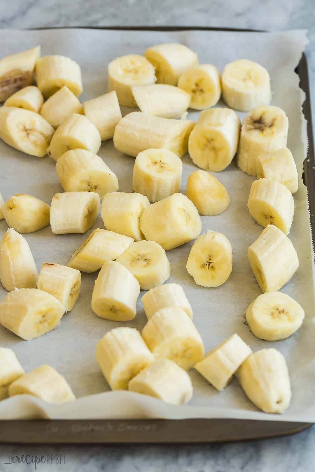 How to freeze bananas 3 different ways, which means you can stock up and have less waste. Perfect for baking, smoothies, cold drinks and more! #banana #bananas #mealprep #baking | food prep | how to freeze fruit | banana recipes | baking with bananas | freezing tips sliced bananas on a parchment lined baking sheet.