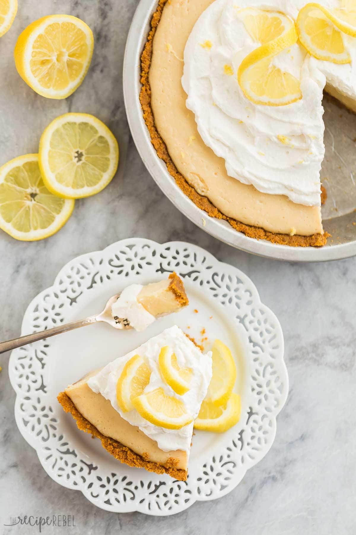 This Lemon Icebox Pie is the perfect combination of sweet and tangy, made with condensed milk, egg yolks and tons of fresh lemon, topped with sweetened whipped cream for an irresistible lemon dessert! #lemon #dessert #pie #recipes #pierecipe | lemon pie | lemon desserts | lemon recipes | easy pie recipes | summer dessert overhead image of a slice of lemon pie on a white plate next to the whole pie.