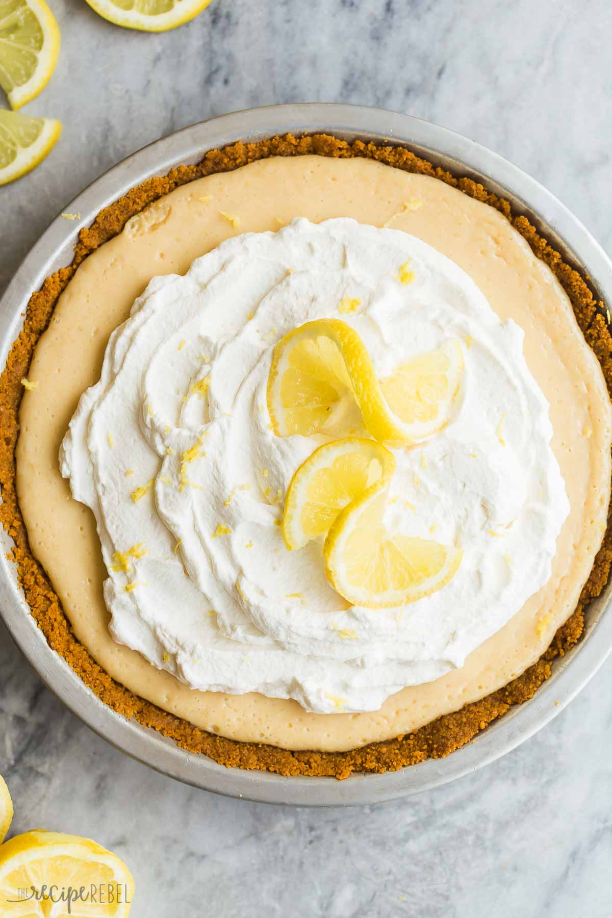 This Lemon Icebox Pie is the perfect combination of sweet and tangy, made with condensed milk, egg yolks and tons of fresh lemon, topped with sweetened whipped cream for an irresistible lemon dessert! #lemon #dessert #pie #recipes #pierecipe | lemon pie | lemon desserts | lemon recipes | easy pie recipes | summer dessert overhead image of whole lemon icebox pie.