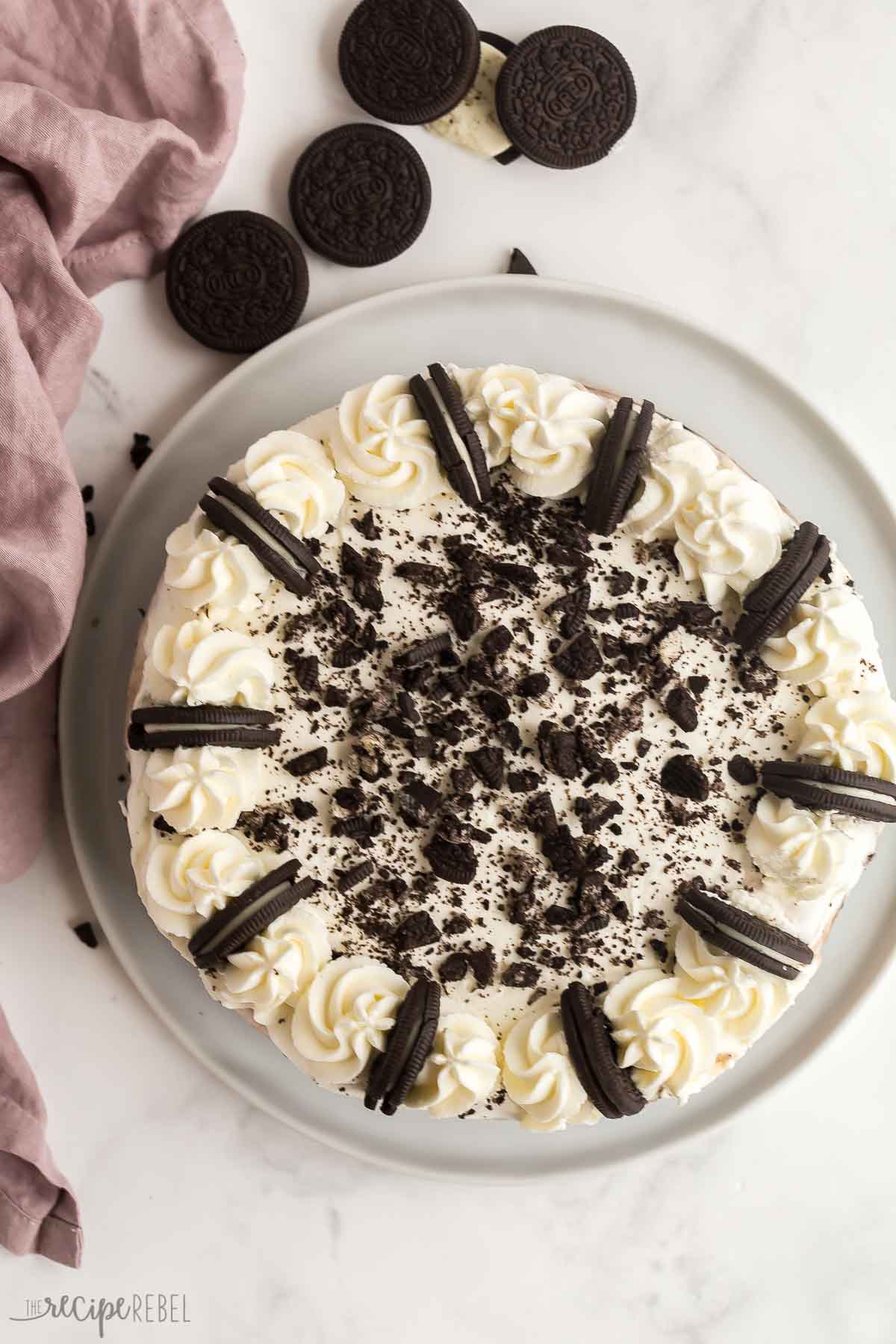 This Oreo Ice Cream Cake is made with an Oreo crust, chocolate ice cream, vanilla ice cream, a rich fudge layer and topped with whipped cream -- for Oreo lovers only! #oreo #icecream #dessert #recipe | oreo desserts | ice cream desserts | ice cream recipes | oreo recipes | summer dessert | easy dessert overhead image of whole oreo ice cream cake with whipped cream and oreos.