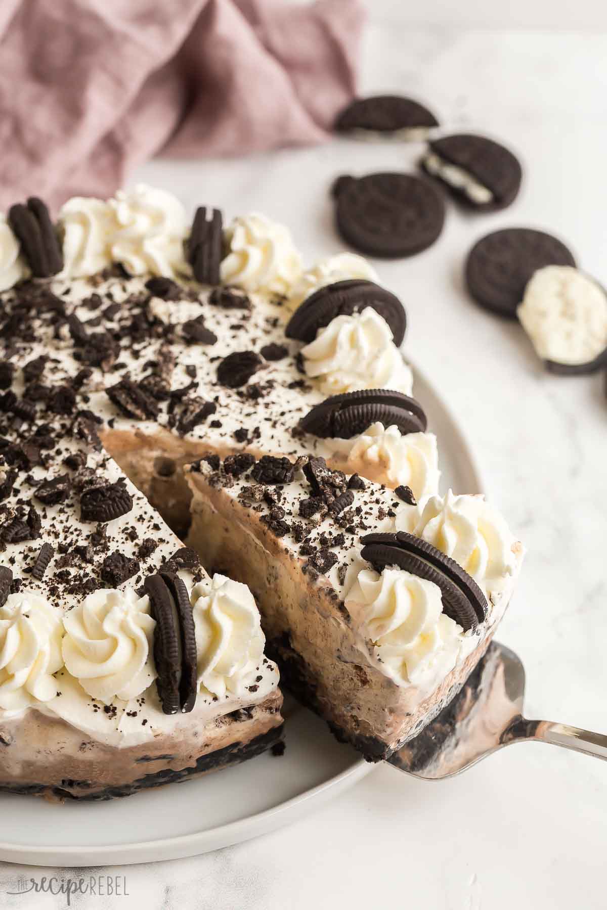 This Oreo Ice Cream Cake is made with an Oreo crust, chocolate ice cream, vanilla ice cream, a rich fudge layer and topped with whipped cream -- for Oreo lovers only! #oreo #icecream #dessert #recipe | oreo desserts | ice cream desserts | ice cream recipes | oreo recipes | summer dessert | easy dessert slice of oreo ice cream cake being pulled out of whole.