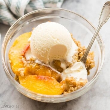 square image of a bowl of peach crisp with vanilla ice cream.