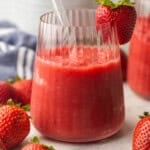 skinny slush in a glass cup with strawberries beside.