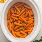 white slow cooker filled with cooked carrots.