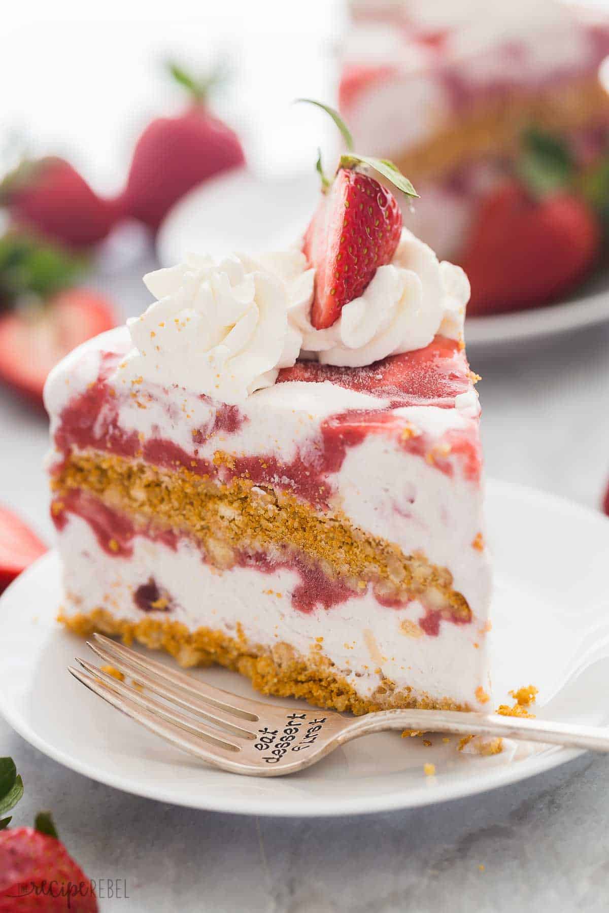 This Strawberry Shortcake Ice Cream Cake is a show-stopping ice cream dessert! Made with crushed shortbread cookies, strawberry shortcake ice cream, and homemade strawberry sauce, it's a no bake dessert everyone will love. #icecream #dessert #strawberry #recipe | strawberry recipes | ice cream recipes | ice cream dessert | dessert recipe | easy recipes | summer dessert slice of strawberry shortcake ice cream cake on a white plate with fork.