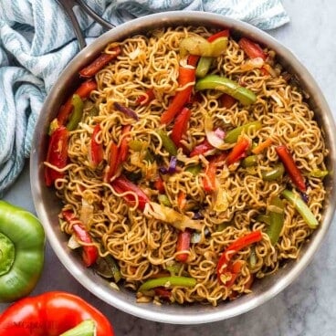 square overhead image of vegetable lo mein in a steel skillet.