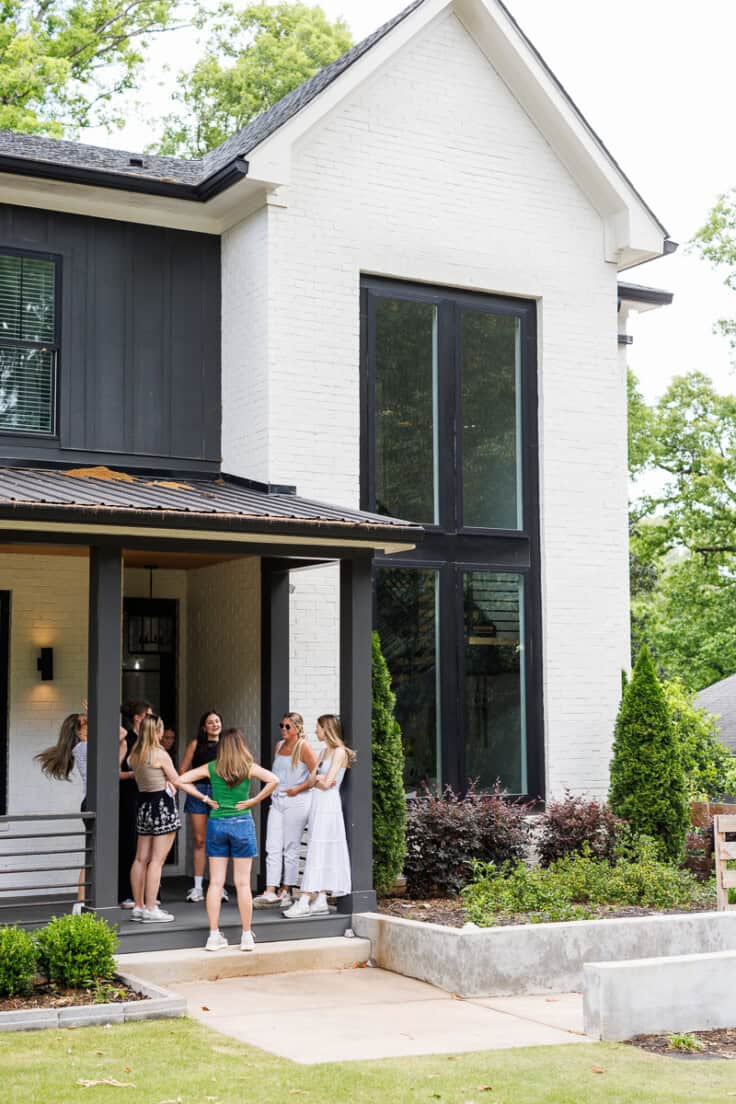 women standing in a group outside a house talking.