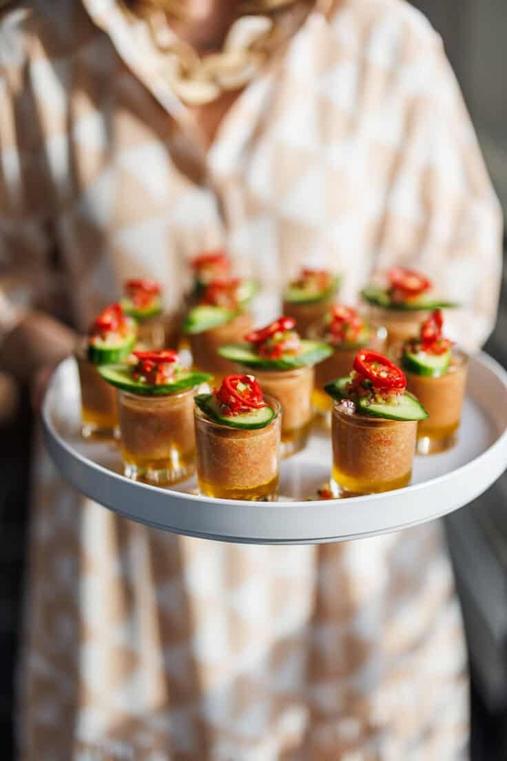 shooter glasses of gazpacho with cucumber on top.