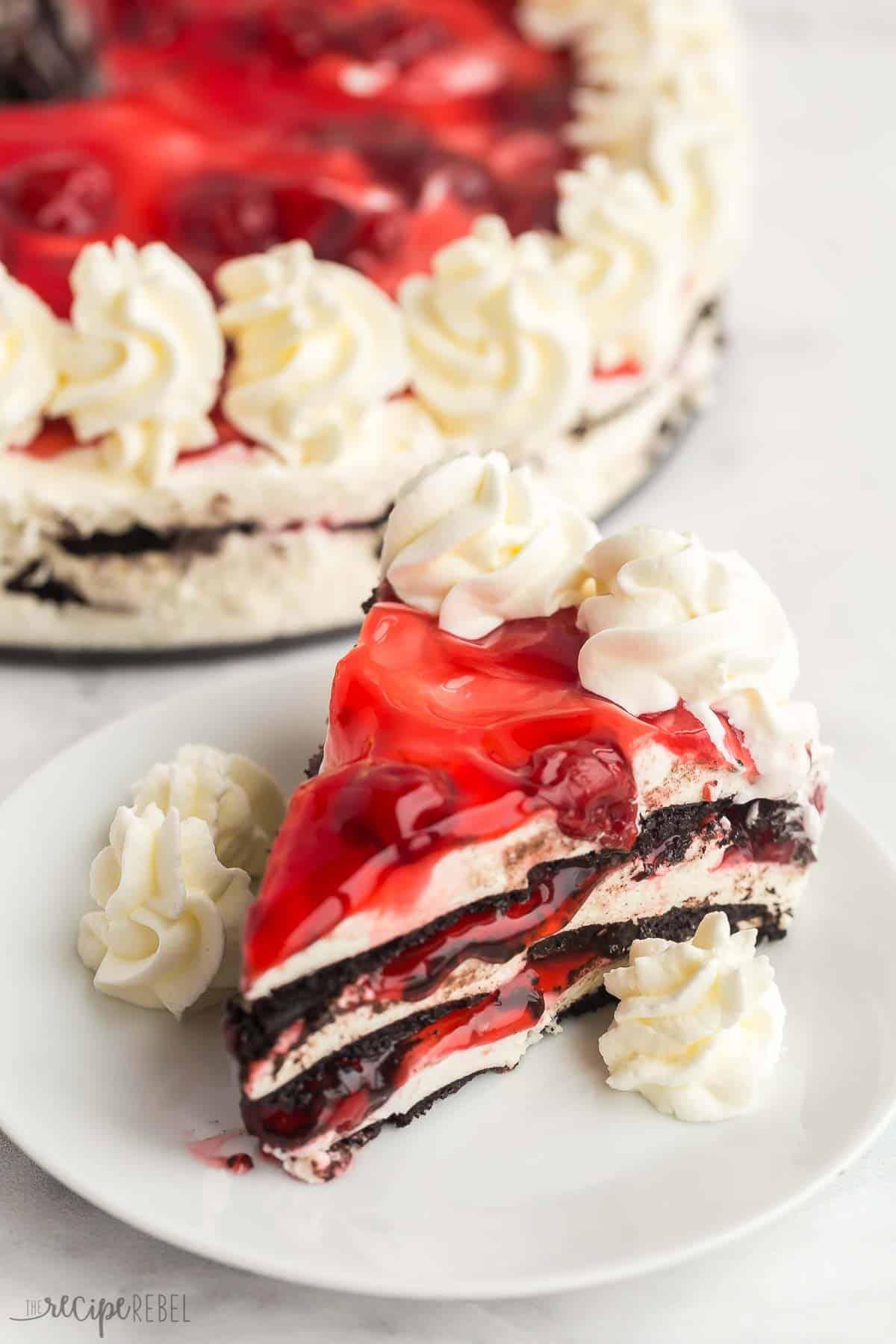 piece of no bake chocolate cherry icebox cake on a white plate with whipped cream.