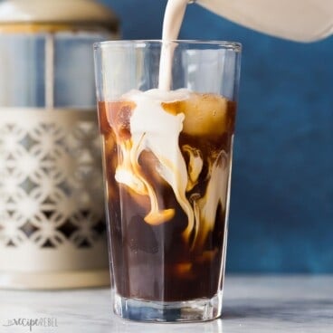 square image of cream being poured into a glass of cold brew coffee.