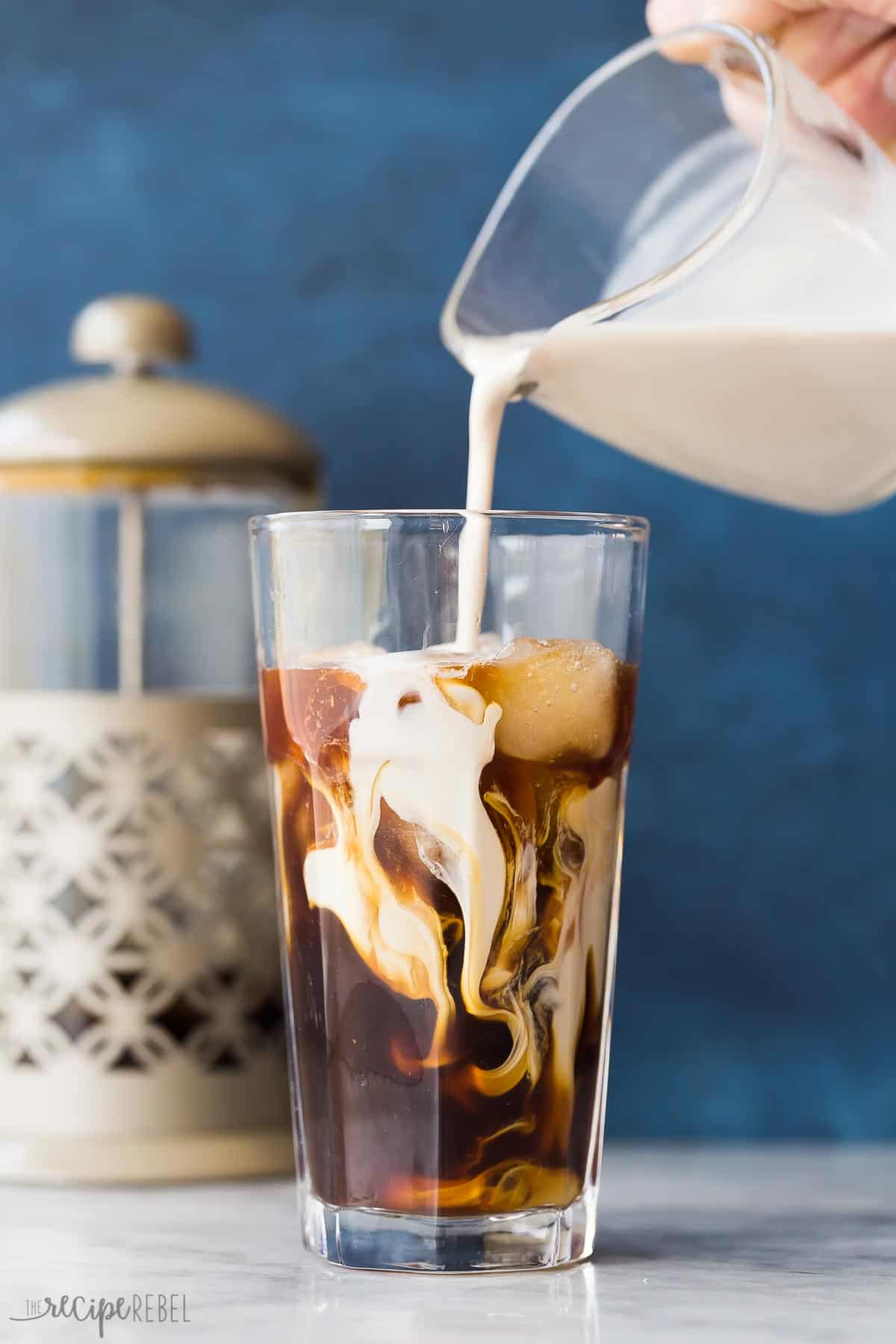 How to make Cold Brew Coffee that is easy, smooth and perfect for summer sipping! No fancy equipment required (just some good coffee 😉 ) #coffee #drink #recipe | coffee drinks | iced coffee | summer drinks | cold drinks | summer recipes | easy recipes cream being poured into a glass of iced coffee.