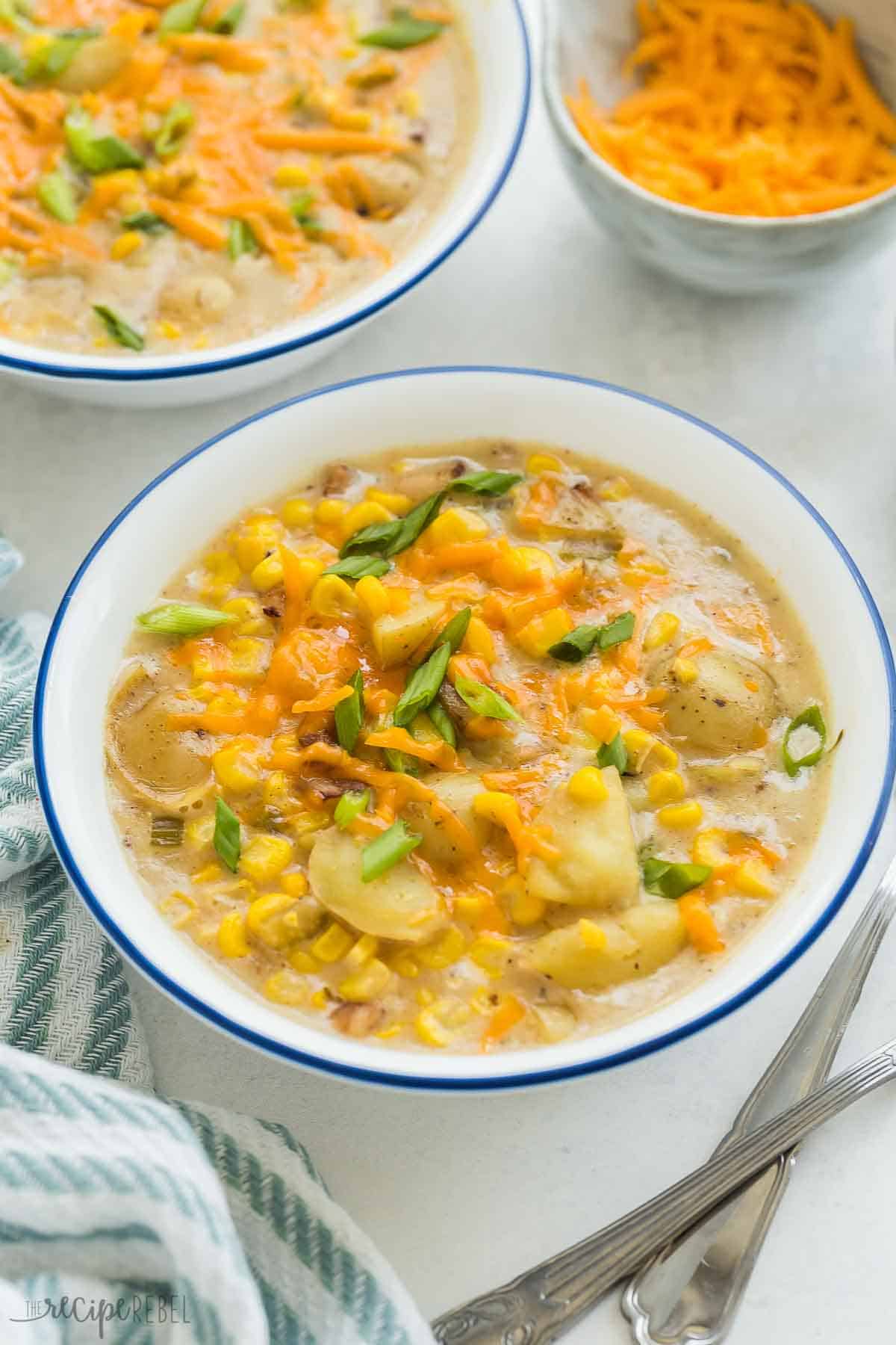 This Instant Pot Potato Corn Chowder is an easy pressure cooker soup recipe that is loaded with creamy potatoes, fresh corn, and smoky bacon. It's perfect for summer or winter! #chowder #corn #soup #recipe #instantpot #pressurecooker | instant pot soup recipes | healthy soup | potato soup | corn recipes | summer recipes | comfort food | easy dinner ideas close up image of instant pot corn chowder in a white bowl with blue trim.