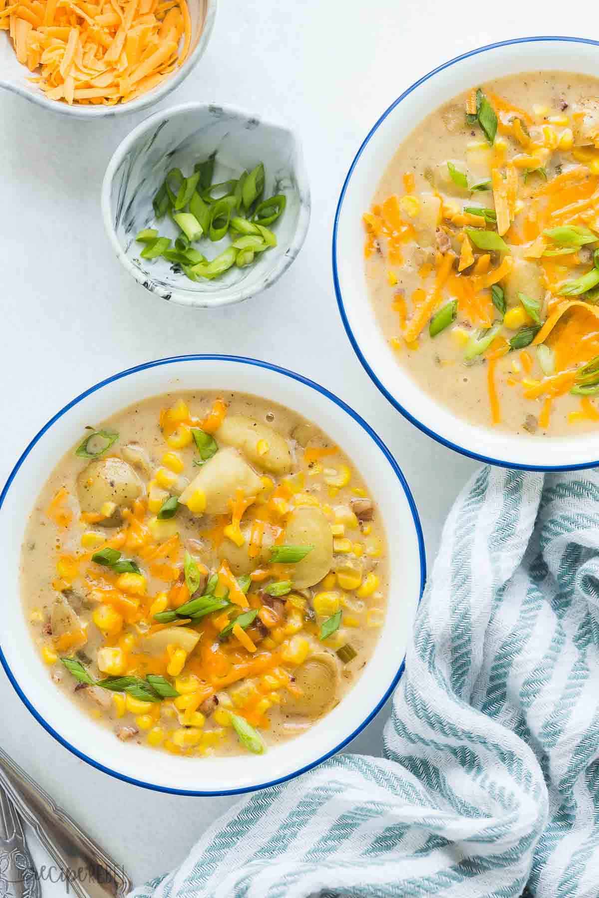 This Instant Pot Potato Corn Chowder is an easy pressure cooker soup recipe that is loaded with creamy potatoes, fresh corn, and smoky bacon. It's perfect for summer or winter! #chowder #corn #soup #recipe #instantpot #pressurecooker | instant pot soup recipes | healthy soup | potato soup | corn recipes | summer recipes | comfort food | easy dinner ideas overhead image of two bowls of potato corn chowder on a white background.