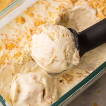 square image of no churn coconut ice cream with metal scoop scooping from loaf pan.