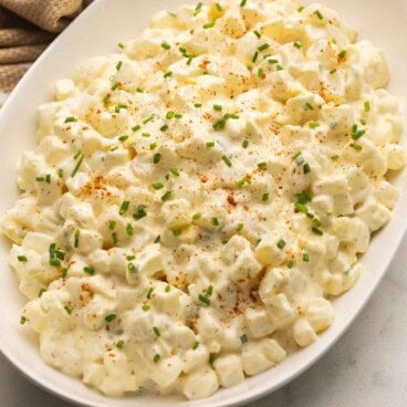a dish of potato salad with chopped green onions on top.