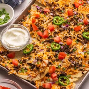 a pan of nachos topped with jalapenos.